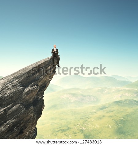 Businessman Sitting On A Peak With Cup Of Coffee