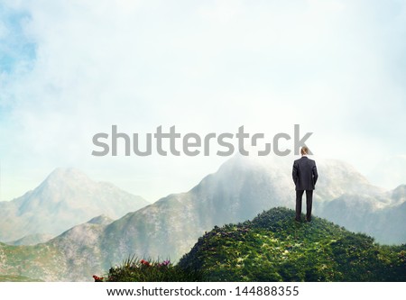 Businessman standing on a peak