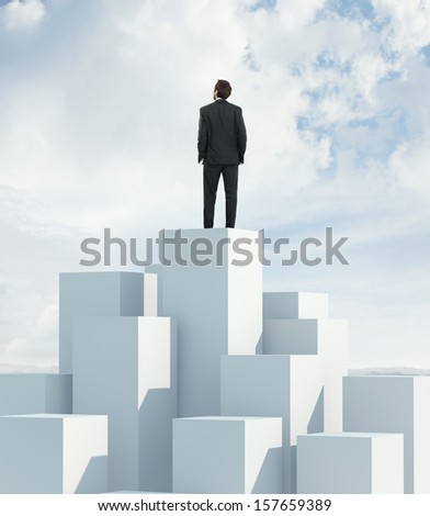 Man standing on highest cube and looking at sky
