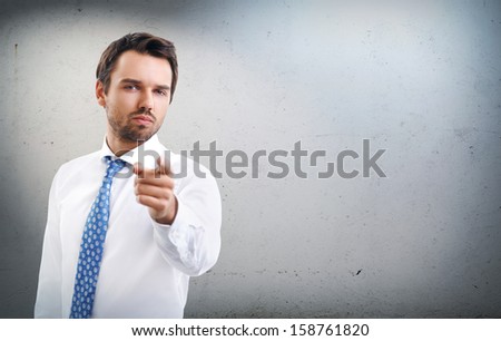 Handsome young businessman points finger at you