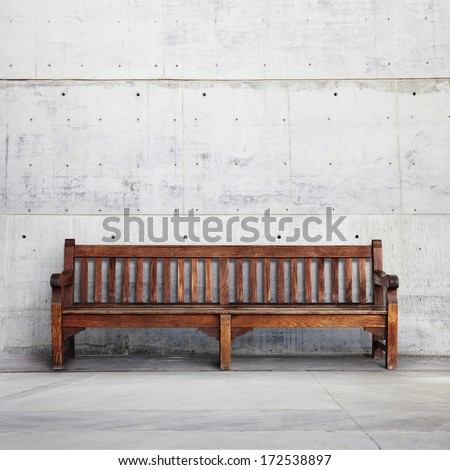 Old wooden bench on bright concrete background