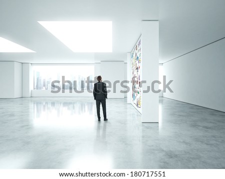 Businessman standing in empty bright office with business strategy on the wall