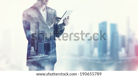 Double exposure of city and business man using digital tablet