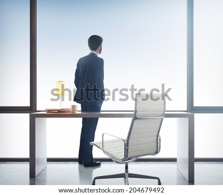 Businessman standing in office and looking through window