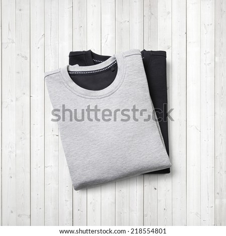 Black and grey jumpers on white wood background