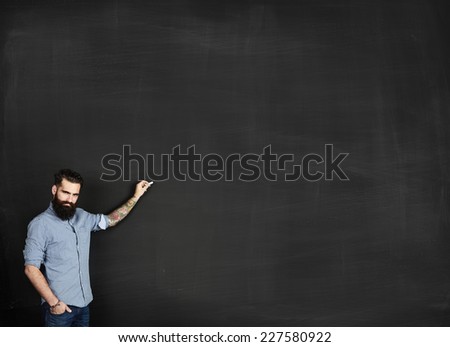 Tattooed man draws on a chalkboard