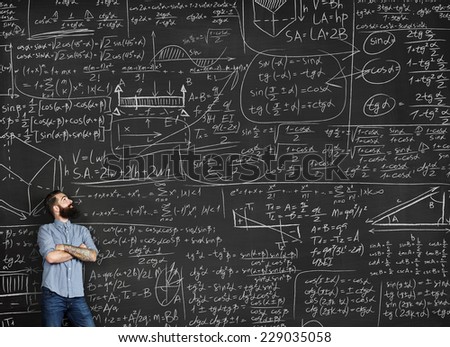 Tattooed man looking at chalkboard with formulas