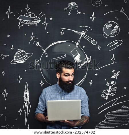 Bearded man with laptop thinks about space