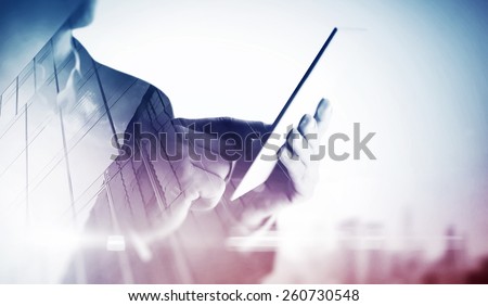 Double exposure of city and hands using tablet