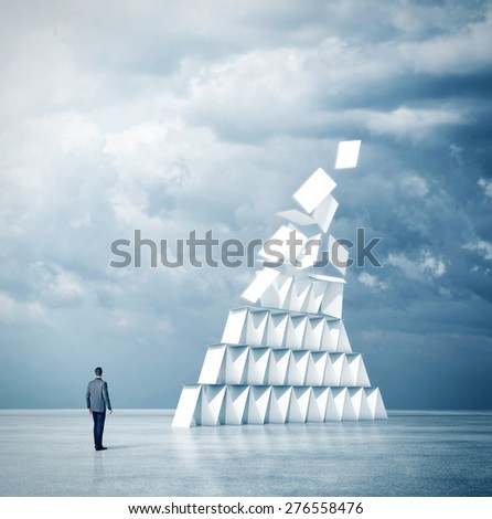 Businessman looks at house of cards. 3d rendering
