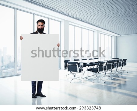 Bearded businessman holding blank canvas at contemporary office