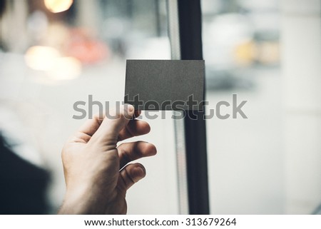 Male hand holding black business card on the background of city