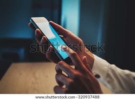 Close up of girl`s hands sending text message in cafe