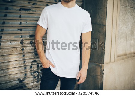 Bearded hipster wearing white blank t-shirt and blue jeans, standing on the street