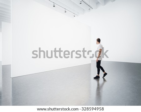 Empty gallery interior with white canvas and man.