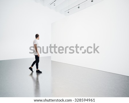 Young man walking in the empty, white gallery