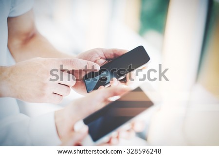 Man and young woman holding in hands their gadgets. The man showing something on the screen