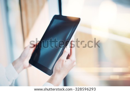Blank tablet holding in woman hands on the blured background.