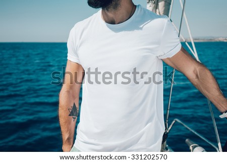 Photo of young bearded man standing on a yacht and looking at the horizon.