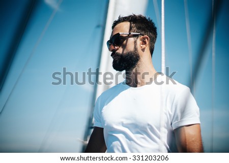 Portrait of young man standing on a yacht and looking at the horizon.