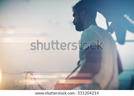 Portrait of young bearded man standing on a yacht and looking at the horizon. Visual effects