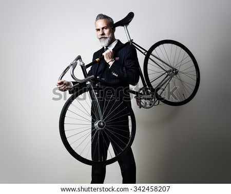Portrait of a handsome middle aged man wearing suit and holding his classic bicycle on the shoulder.