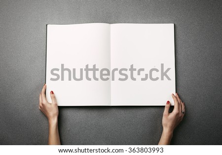 Female hands holding a big open book. Horizontal