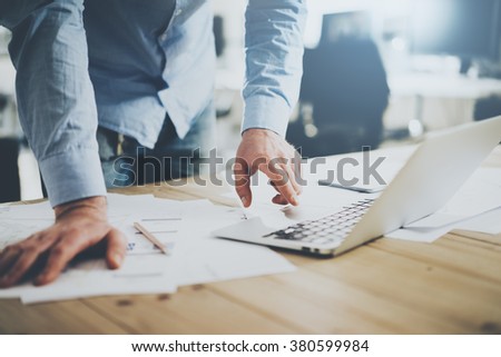 Businessman working in modern cretive studio. Using generic design laptop. Architectural project on table. Blurred background, horizontal mockup.