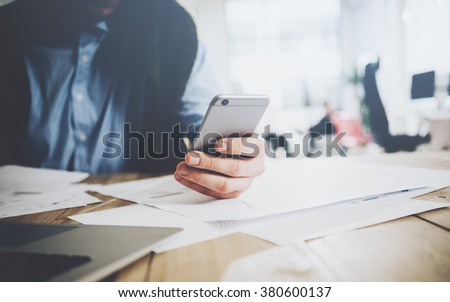 Workspace lifestyle concept. Businessman using smartphone. Generic design laptop on the table. Blurred background, horizontal mockup.
