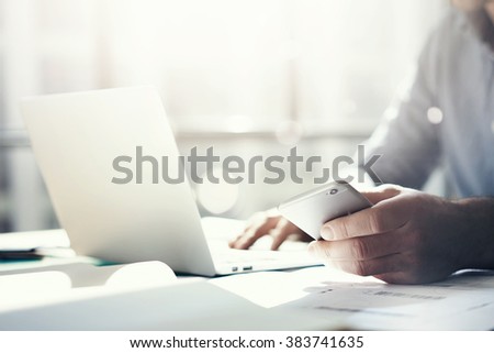 Businessman working with generic design notebook. Holding smartphone in hands. Horizontal, sunlight effects