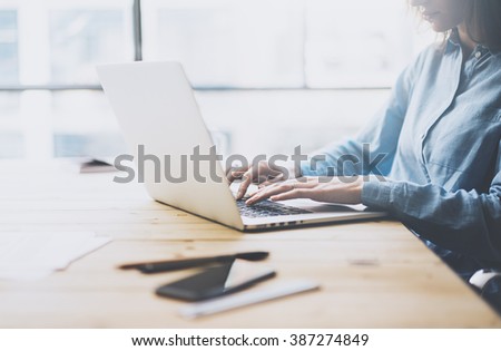 University work process concept. Student girl working new project with generic design laptop.  Smartphone wooden table, texting message. Blurred background, film effect. Horizontal