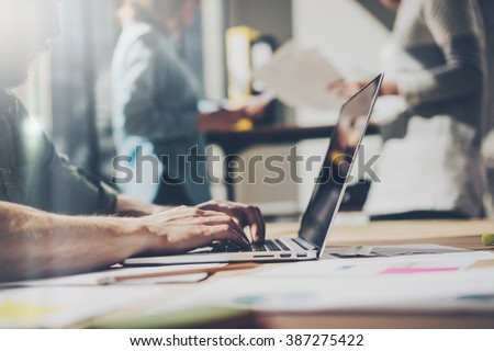 Bearded businessman working with team new project. Generic design notebook on wood table.  Analyze plans hands, keyboard. Blurred background. Film effect