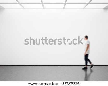 Photo of man in modern gallery looking at the empty canvas. Blank mockup, motion blur