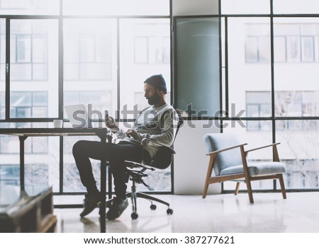 Businessman on modern loft office. Texting message smartphone. Generic design notebook wood table. Horizontal mockup. Film effect.