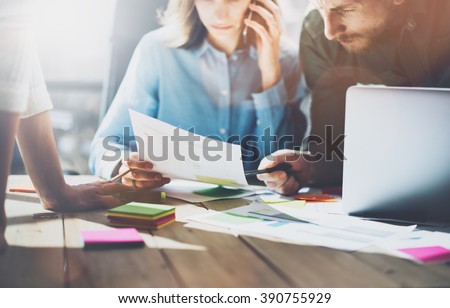 Team succes. Photo young business managers  working with new startup project in modern loft. Generic design notebook on wood table, talking smartphone, papers, documents. Horizontal, sunlight effect
