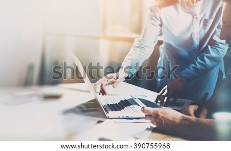 Team project. Photo young talent managers working with new startup project in modern office. Generic design notebook on wood table. Horizontal, sunset effect, blurred