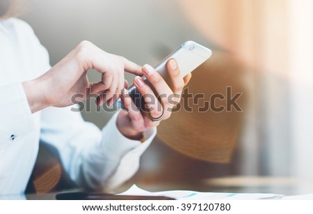 Closeup photo businesswoman working new startup project modern office.Contemporary smartphone holding female hands and touching screen. Horizontal, film effect. Blurred