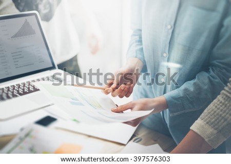 Team job succes.Closeup photo young business managers  working with new startup project in office.Analyze document, plans. Contemporary notebook on wood table, papers, documents. Horizontal, blurred