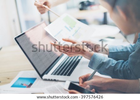 Coworking team.Closeup photo young business managers  working with new startup project in office.Analyze document,statistics plans screen. Notebook on wood table,papers,documents. Horizontal, blurred