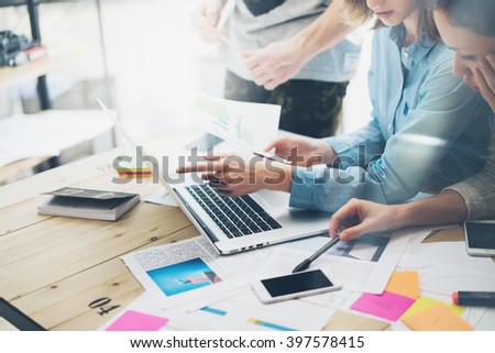 Creative team coworking project.Photo business managers working with new startup in modern loft.Analyze reports,plans. Notebook on wood table, papers, documents, statistics. Horizontal, blurred