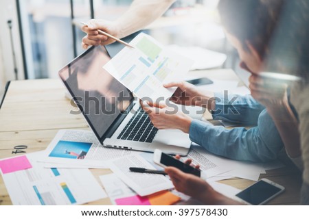 Team account manager project work.Photo business managers working with new startup in modern loft.Analyze reports,plans. Notebook on wood table, papers, documents, statistics. Horizontal, blurred