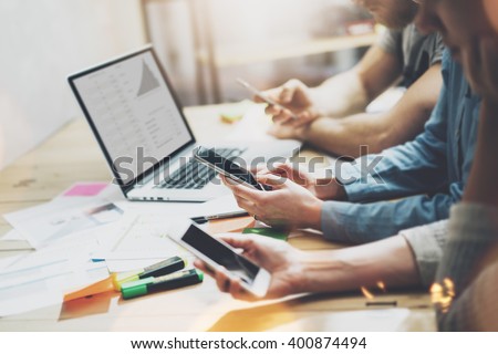 Digital world. Photo young business managers crew working with new startup project.Notebook on wood table. Using modern smartphones, typing message, analyze plans screen. Horizontal, film effect.