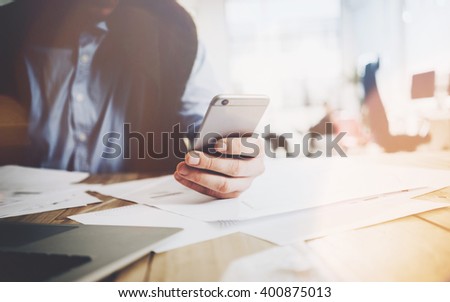 Office world, work process. Businessman working at the wood table with new business project. Man touching screen modern mobile phone. Horizontal mockup. Flares, film effect