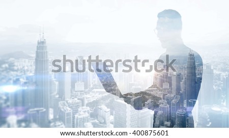 Double exposure photo stylish businessman wearing black shirt and glasses.Banker holding contemporary notebook hands,work online banking.Panoramic view modern skyscraper city background.Soft light