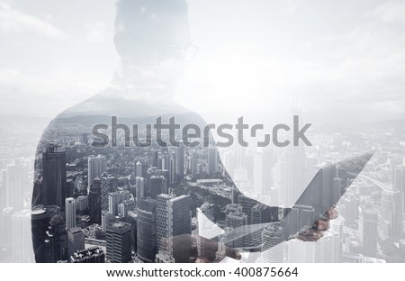 Double exposure bearded businessman wearing black shirt and glasses.Banker holding contemporary notebook hands,work online banking.Modern skyscraper city background.Horizontal mockup