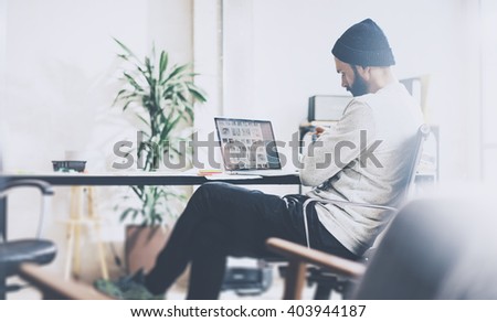 Photo bearded account director working with new project modern studio. Using contemprary notebook on wood table. Creative process. Freelance world. Blurred background, film effect, horizontal
