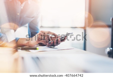 Business process photo. Account manager using mobile phone. Typing contemporary smartphone screen. Horizontal. Film and flares effect. Blurred background