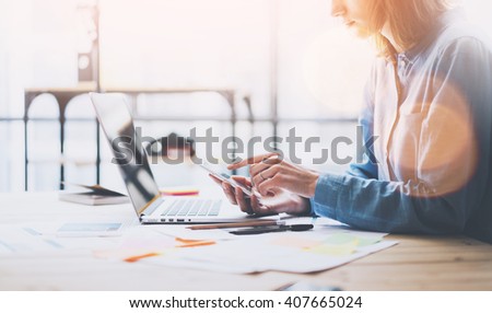 Working process photo. Account manager working wood table with new business project. Typing contemporary smartphone screen. Horizontal. Film and flares effects. Blurred background