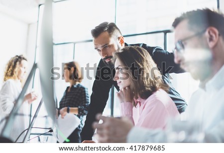 Young professionals work in modern office.Project manager team discussing new idea.Business crew working with startup.Modern desktop computer table,showing presentation.Blurred,film effect.