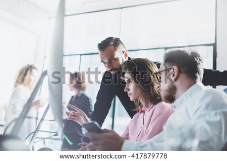 Young professionals work in modern office.Project manager team discussing new idea.Business crew working with startup.Desktop computer table,showing presentation, monitor.Blurred,film effect.